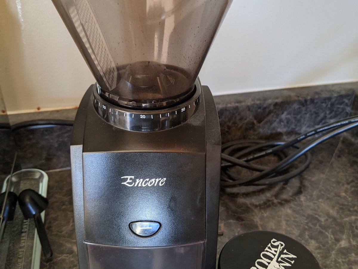 A coffee grinder with a dose of beans on the counter
