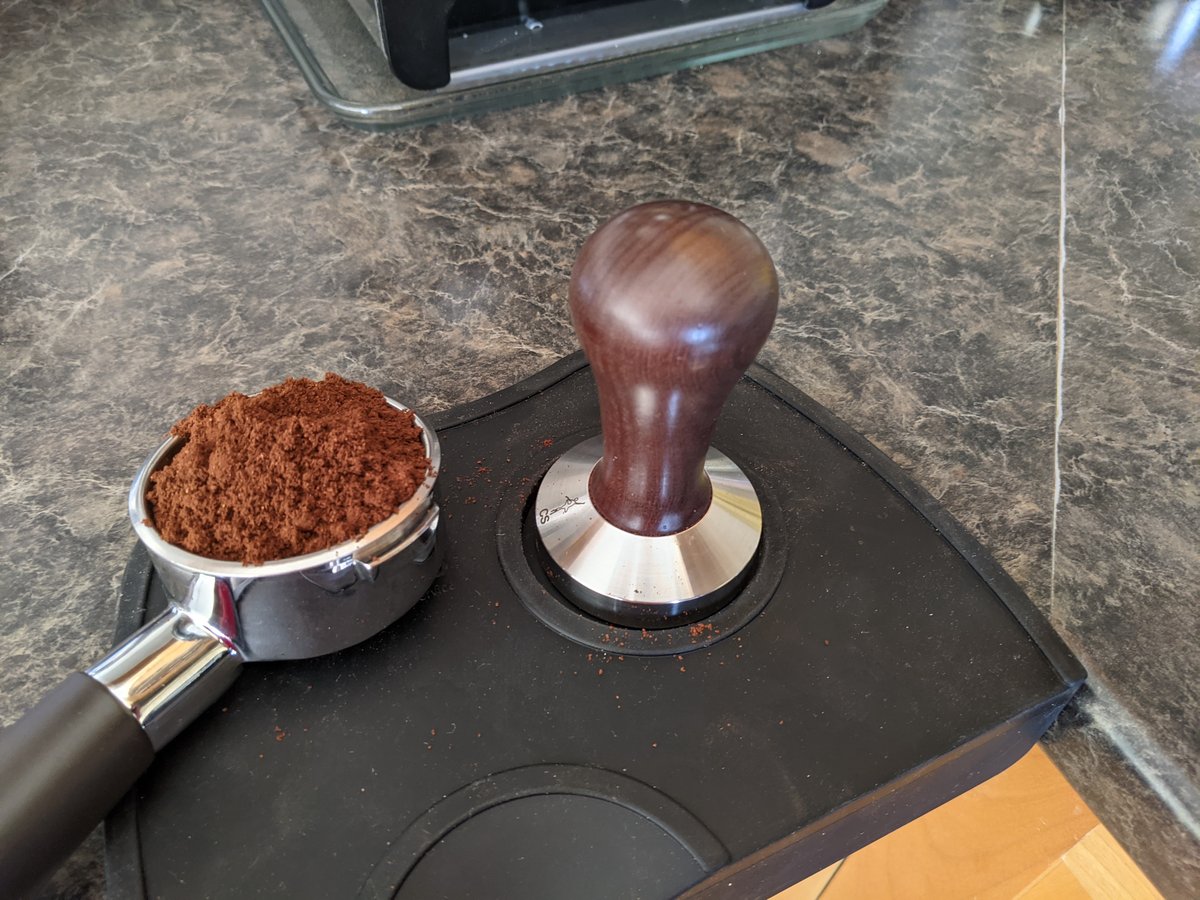 A tamper, scale and portafilter laid out on a wooden counter